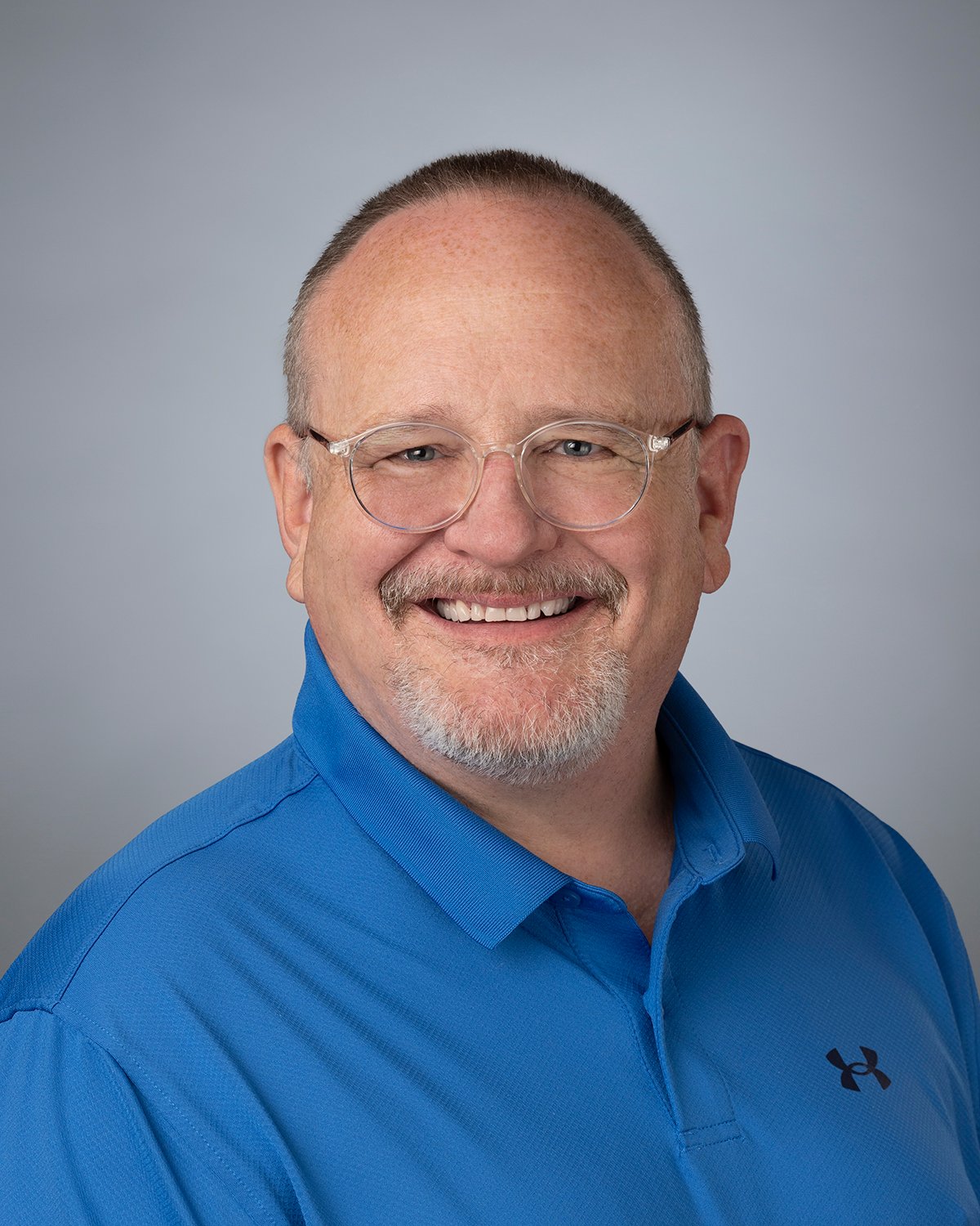 Photo of Scott Butler, a white man with glasses wearing a blue polo shirt.